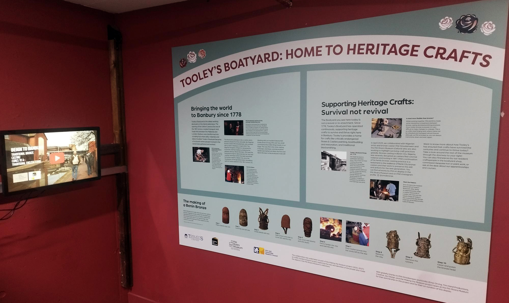 A museum display board and screen in the corner of a room