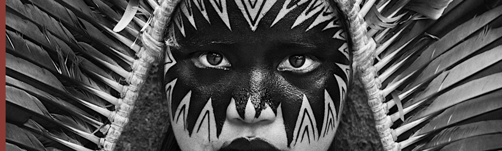 Black and white photo of woman with ornately painted face and feather headdress