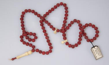 Misbaha, string of prayer beads made of camel bone, each bead is dyed red and incised.