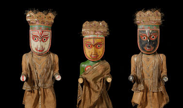 Wooden sculptures with painted faces and dressed in clothes made of metal braided cloth and paper crowns