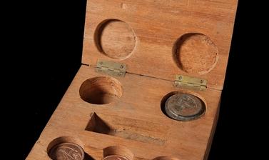 Twenty-three copper alloy medallions housed in a wooden box.