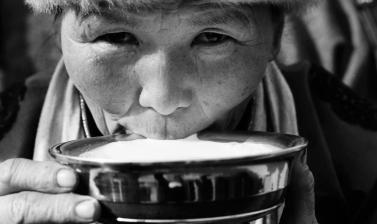 Black and white photo of a person drinking milk from large bowl