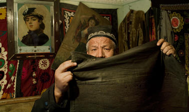 A museum-worker displaying the black hijab commonly worn by Uzbek women before the Soviet Union prohibited Islamic head-covering. Andijan, Uzbekistan. Photograph by Carolyn Drake. March 2007.