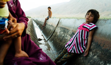 Children cool off in an irrigation canal that flows intermittently through their village. It is their only source of water. Akjar, Tajikistan. Photograph by Carolyn Drake. July 2008.