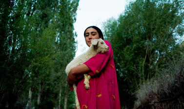 A Pamiri woman carrying home a lamb at dusk. Garm Chashma, Tajikistan. Photograph by Carolyn Drake. July 2008.