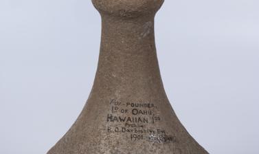 A conical stone pounder with a flared and round base and spherical handle on the top. 