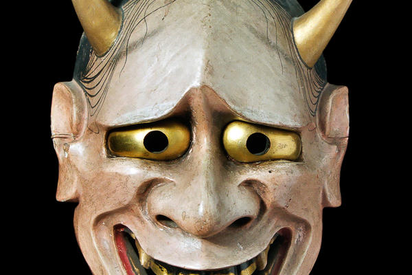 A white faced mask with two bulging eyes and a pair of horns coming out of the top of the head.